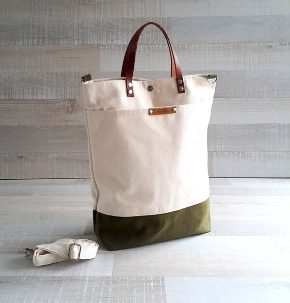 a white and green tote bag sitting on top of a wooden floor next to a pair of shoes