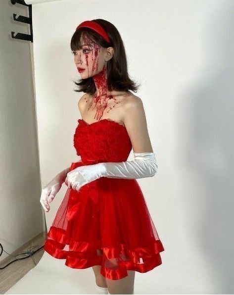 a woman dressed in red and white with blood on her face