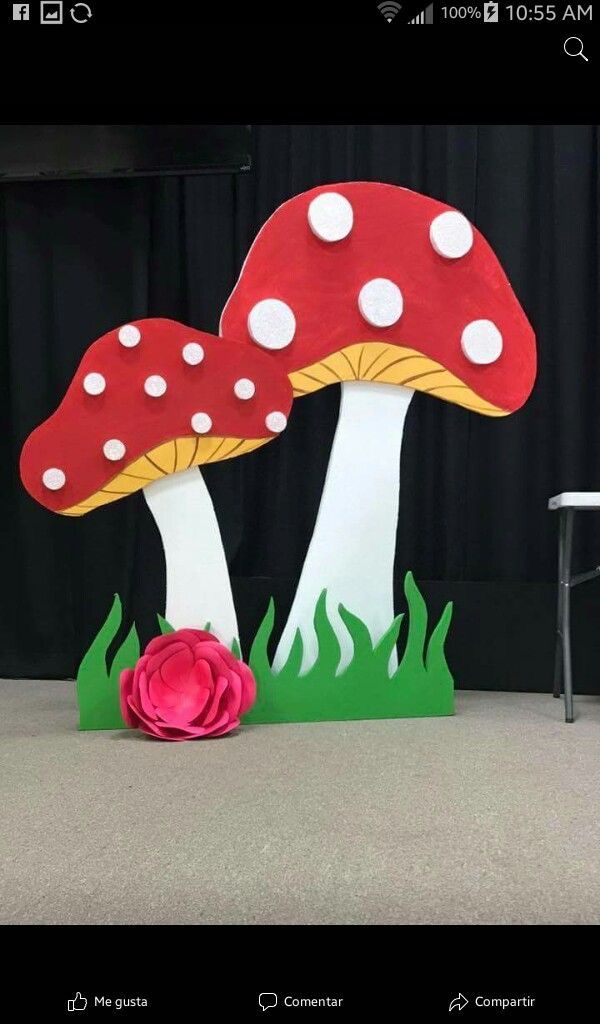 a paper cutout of two mushrooms with a flower in front of them on the ground