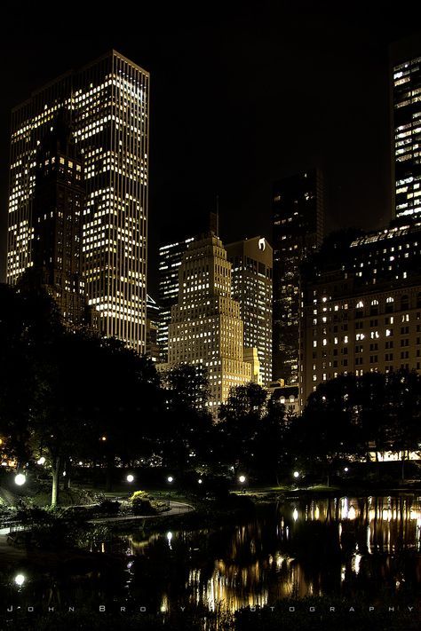 the city is lit up at night with lights reflecting in the water and skyscrapers