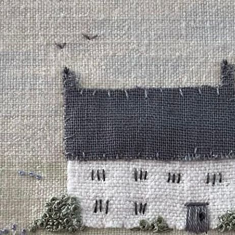 an embroidered house with birds flying over it