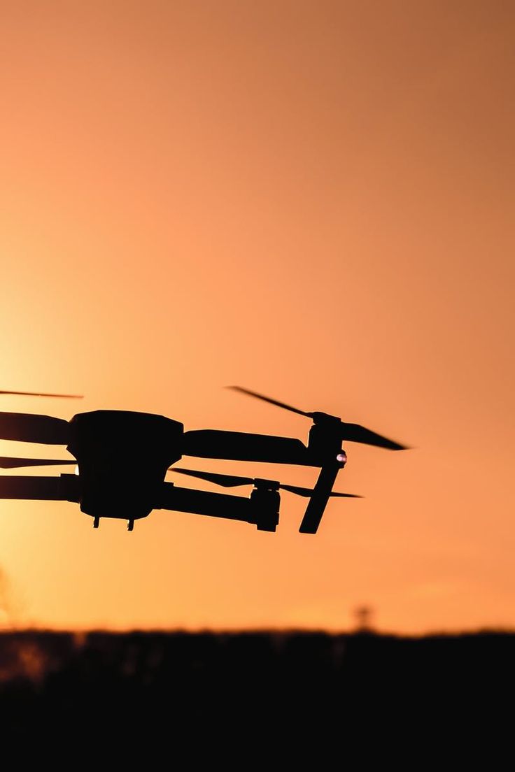 a small propeller plane flying in the air at sunset or dawn with its landing gear down