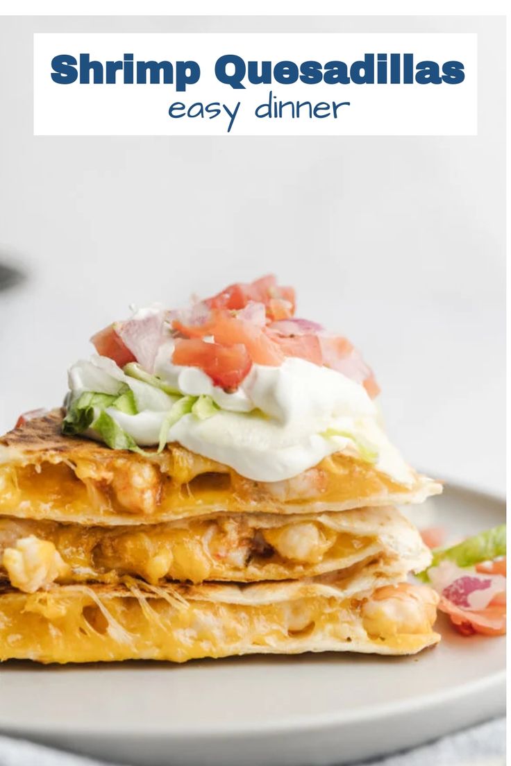 a stack of quesadillas on a plate topped with sour cream and tomatoes