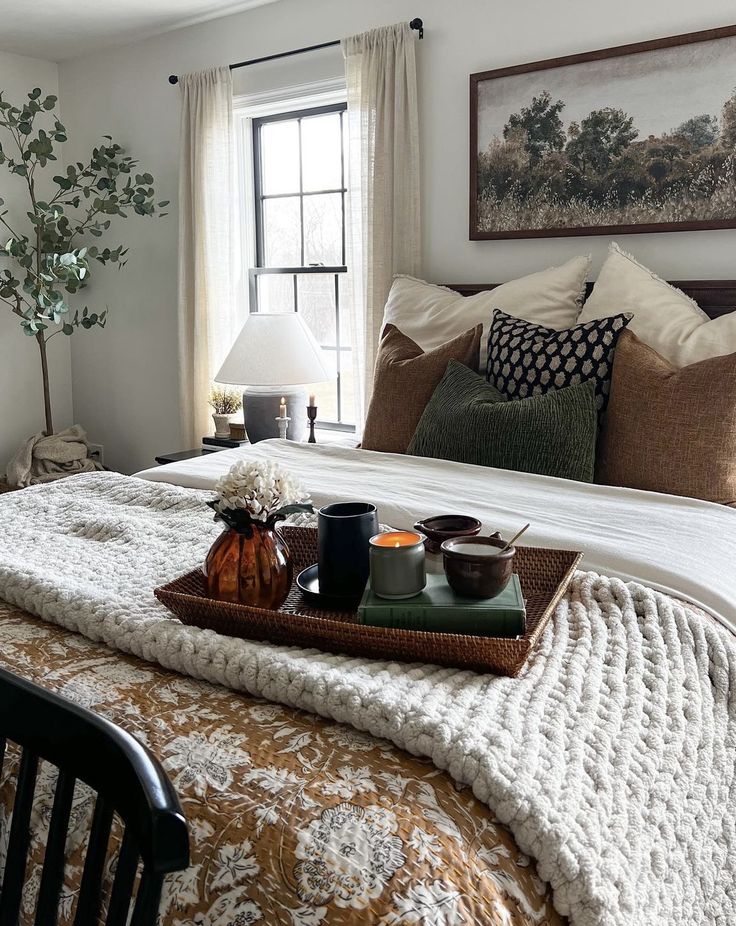 a tray with food on top of a bed next to a window in a bedroom