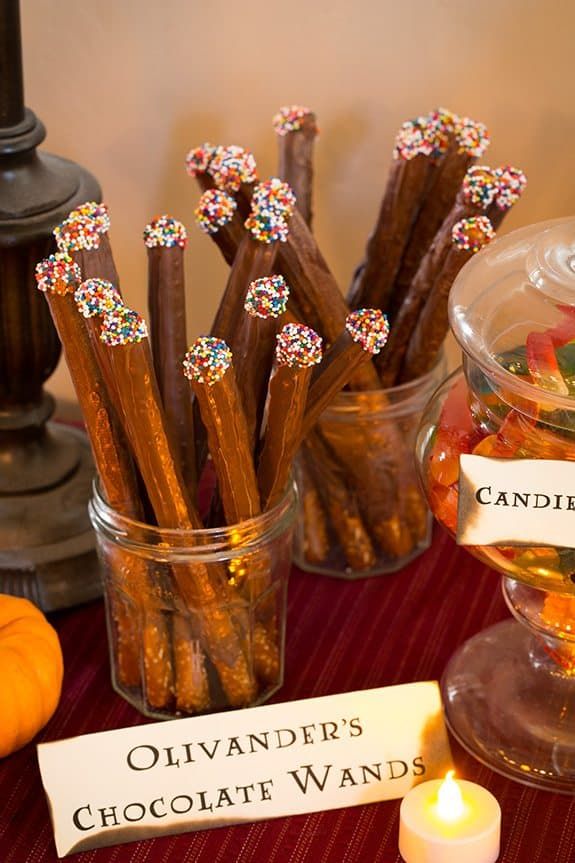 there are many chocolate wands on the table with candles and candies in them