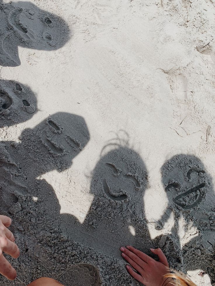 four people are standing in the sand with their shadows on them