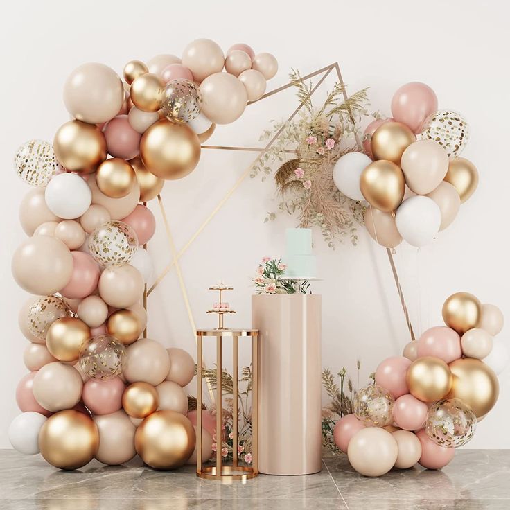 a pink and gold balloon arch on a marble table next to a vase with flowers