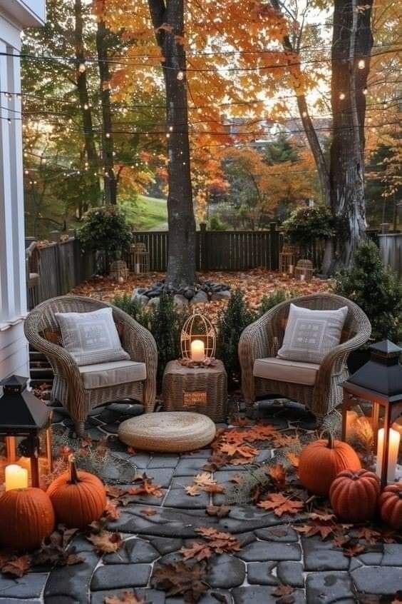 the patio is decorated with fall leaves and pumpkins, lanterns, and wicker furniture