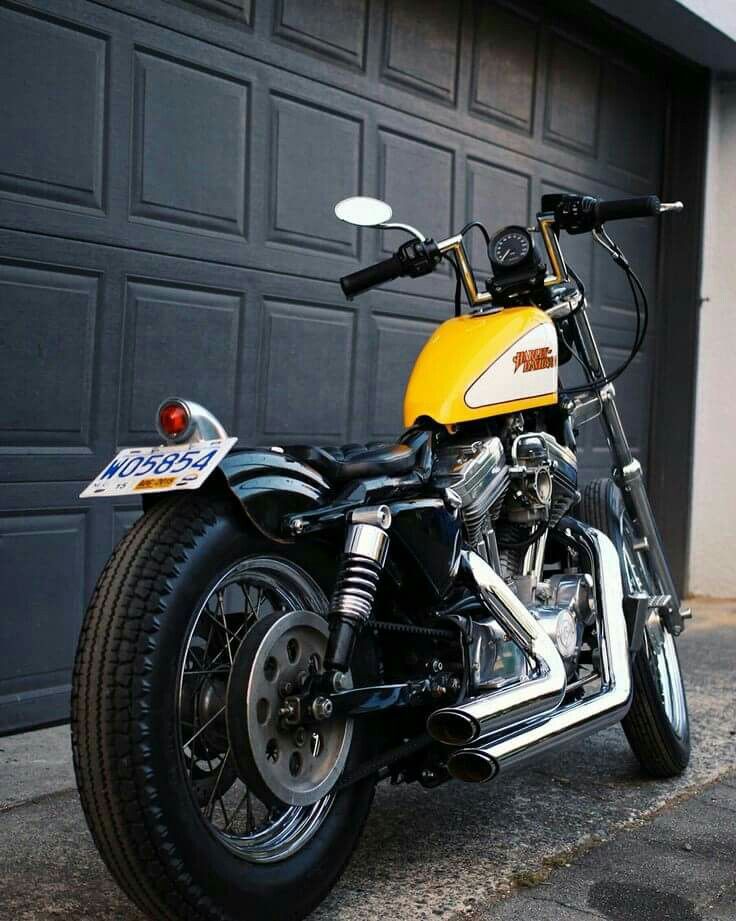 a yellow and black motorcycle parked in front of a garage