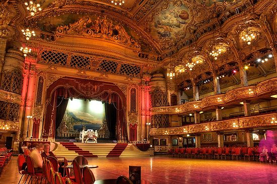 an ornately decorated auditorium with chandeliers and red chairs on the stage,