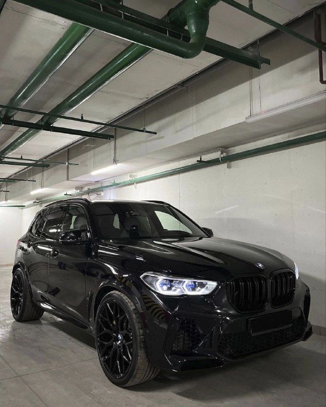 a black bmw suv parked in a parking garage