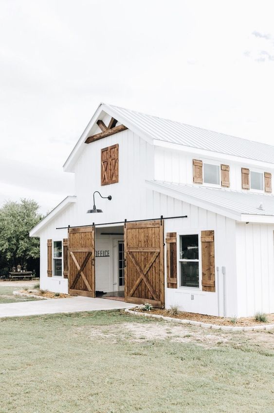 a large white barn with wooden doors and windows