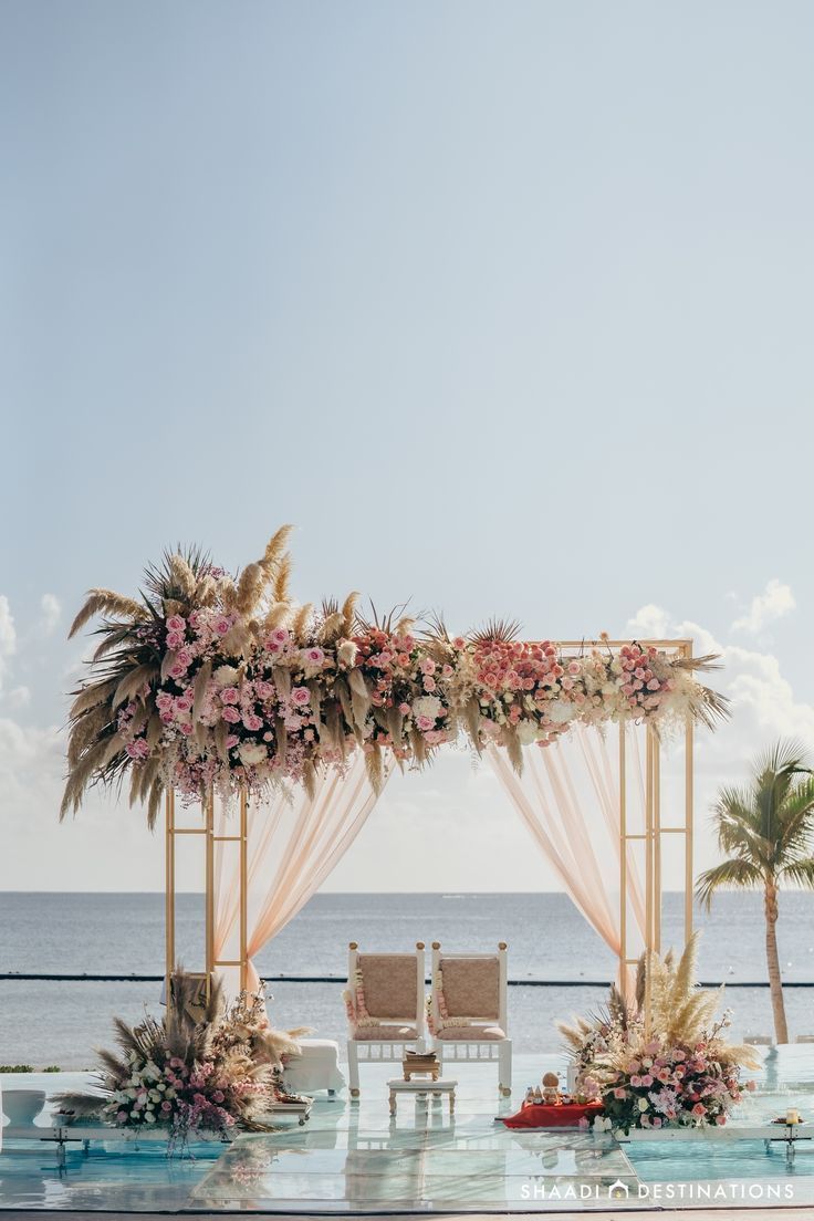 an outdoor wedding set up with flowers and greenery on the side of the beach