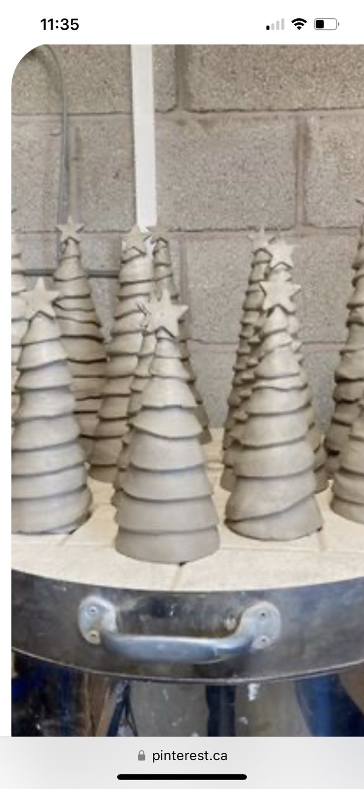 a group of clay trees sitting on top of a table next to a brick wall