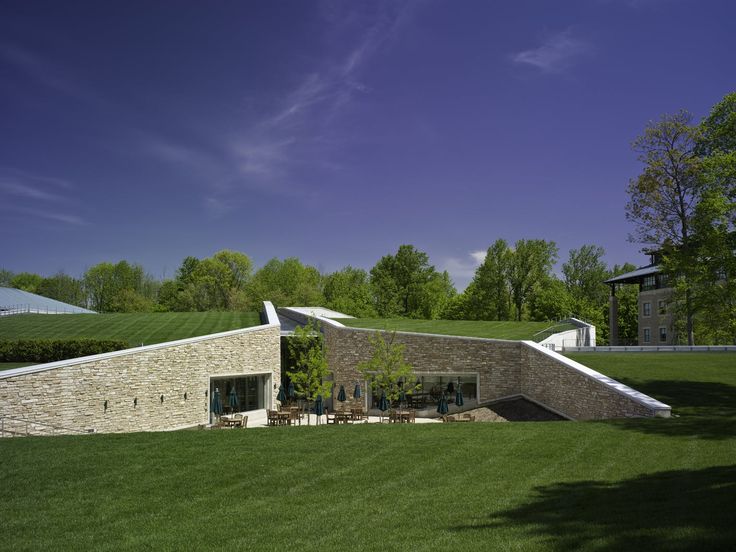 a large grassy field next to a building with a roof made of rocks and grass