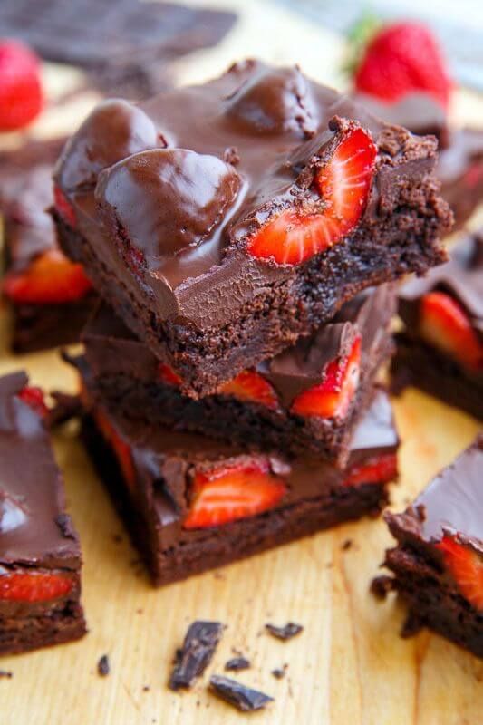 chocolate strawberry brownies stacked on top of each other with strawberries in the background