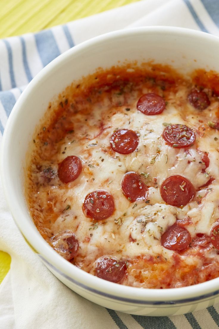 a white bowl filled with pepperoni and cheese on top of a blue and white towel