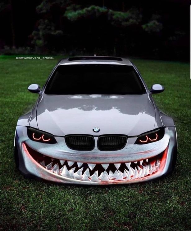 the front end of a silver car with fangs on it's face and mouth