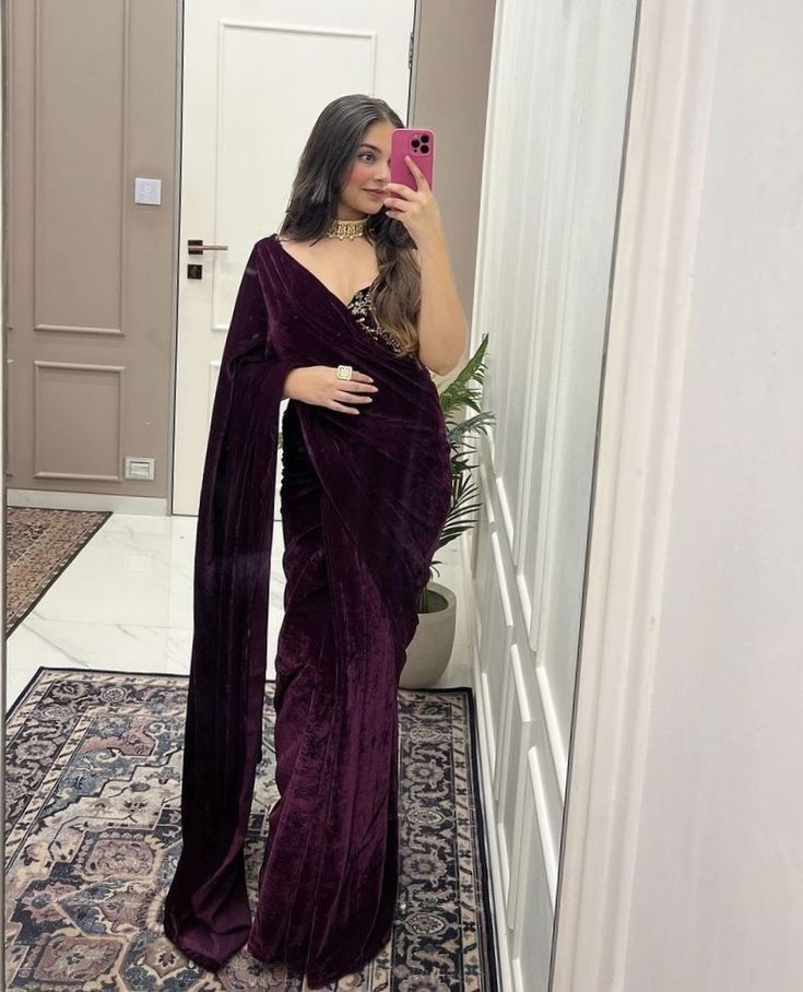 a woman taking a selfie in a bathroom mirror wearing a purple velvet sari