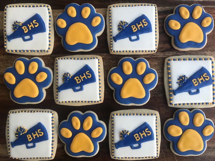 decorated cookies with blue and yellow frosting are arranged in the shape of paw prints