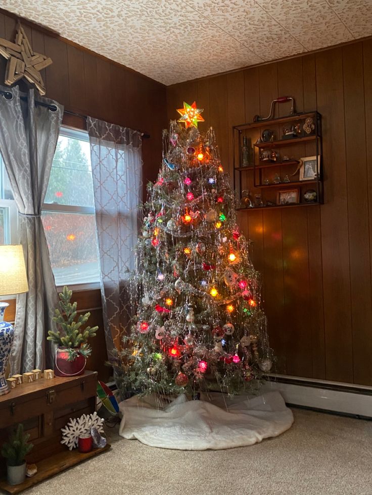 a decorated christmas tree sitting in the corner of a living room next to a window