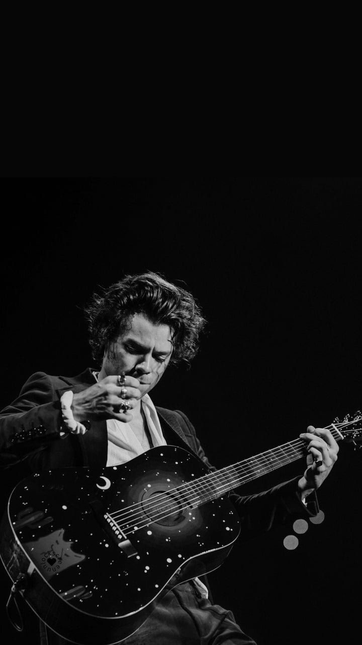 black and white photograph of a man playing an acoustic guitar with his hand on the neck