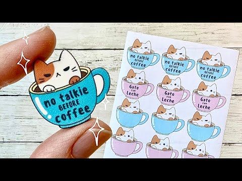 someone is holding up a sticker with cats in a cup on it and there are other stickers