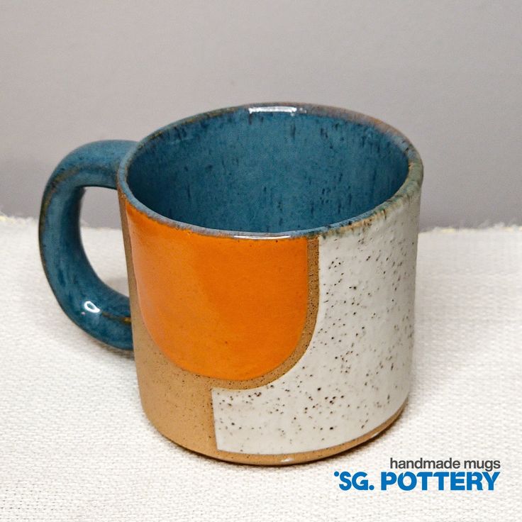 a blue and white coffee cup sitting on top of a cloth covered table next to a wall