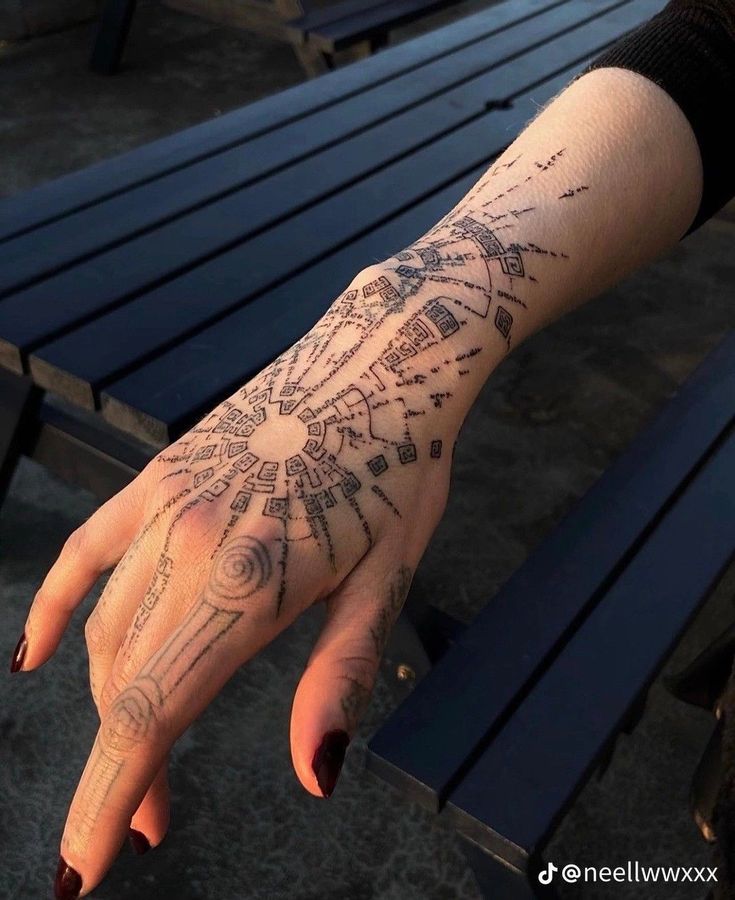 a person's hand with a tattoo on it sitting next to a park bench