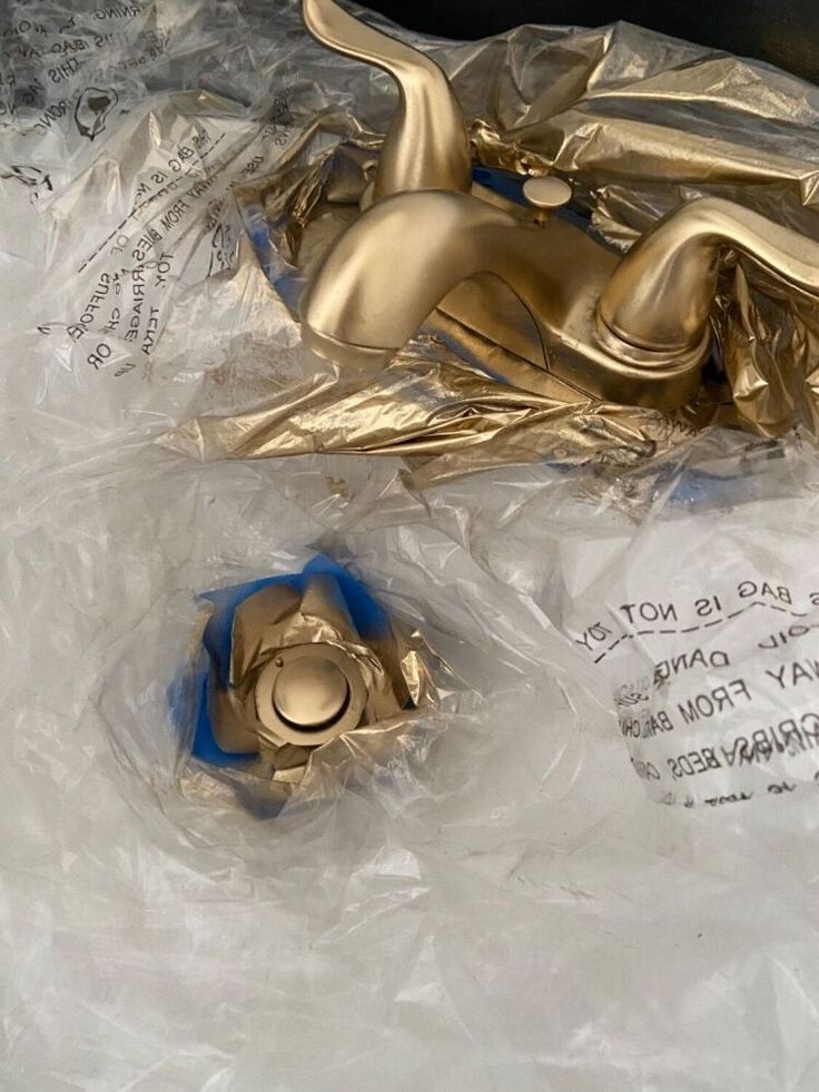 a shiny gold faucet sitting on top of plastic wrapped in plastic wrap next to a blue object