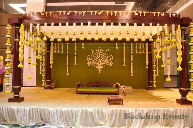 a stage set up for a wedding ceremony with white and yellow decorations on the walls