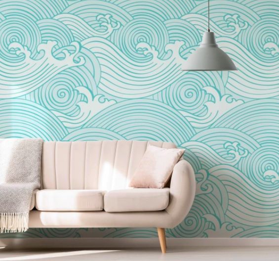 a couch sitting in front of a wall with waves painted on the wall behind it