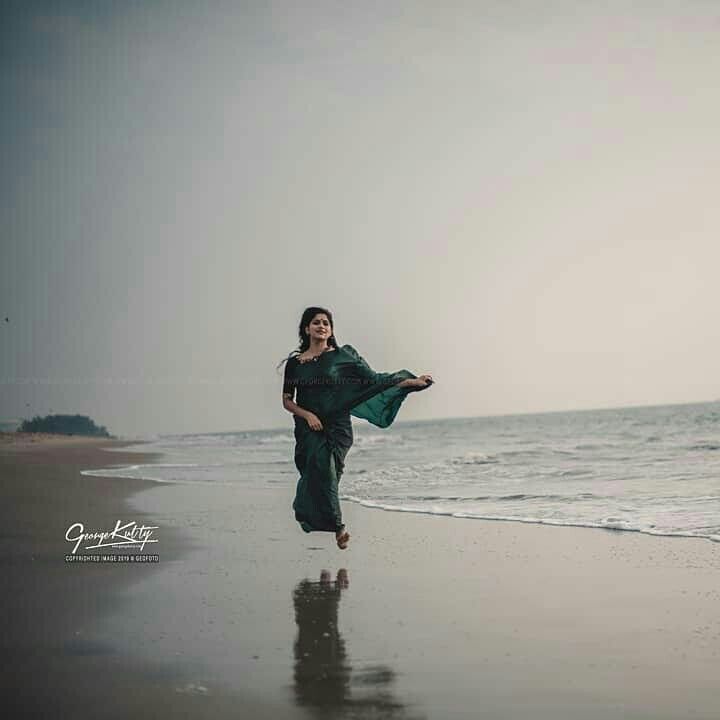 a woman is walking on the beach with her arms in the air as she runs towards the water