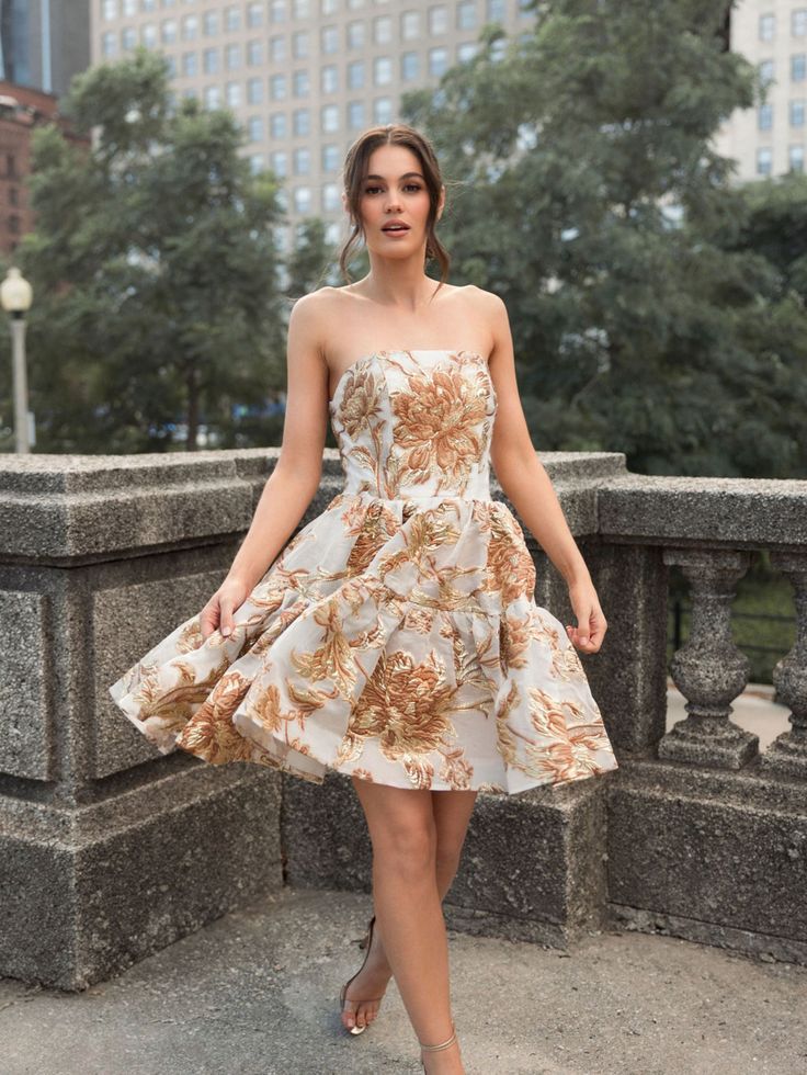 Ieena for Mac Duggal Brocade fabric (100% polyester) Fully lined Strapless A-line skater skirt Floral brocade detailing Concealed back zipper Approx. 35" from top of shoulder to bottom hem Available in Bronze Style #20718 Cocktail A-line Mini Dress With Floral Print, Fitted A-line Strapless Dress With Floral Print, Formal Flared Dress With Ruffles, Evening Strapless A-line Fit And Flare Dress, Fitted Flared-skirt Prom Dress, Evening Fit And Flare A-line Strapless Dress, A-line Floral Print Mini Dress For Wedding, Evening A-line Fit And Flare Strapless Dress, Fit And Flare A-line Strapless Evening Dress