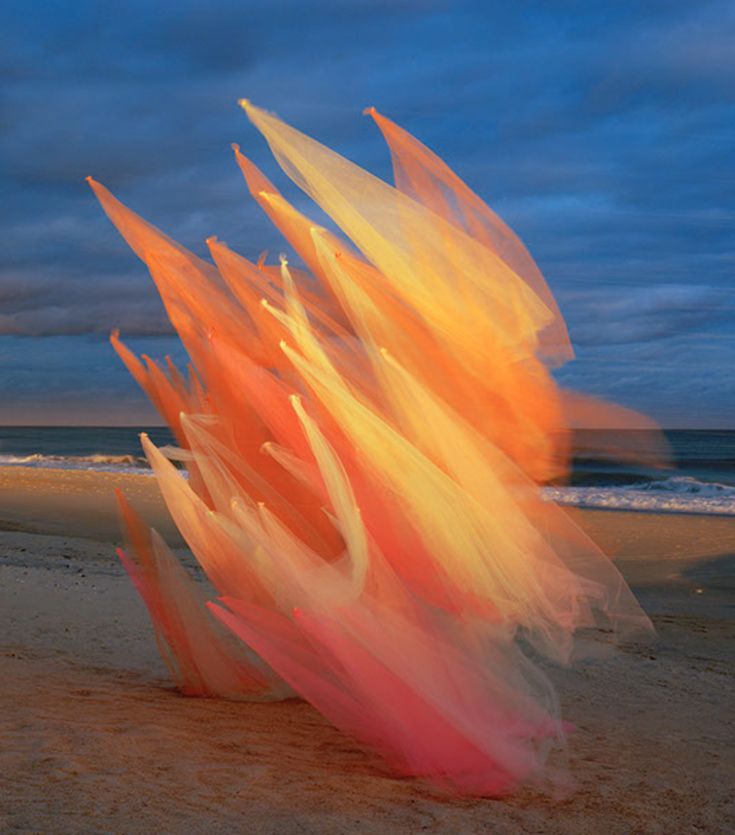 an orange and pink object on the beach at night with dark clouds in the background