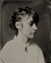 an old black and white photo of a woman with her hair in a messy bun