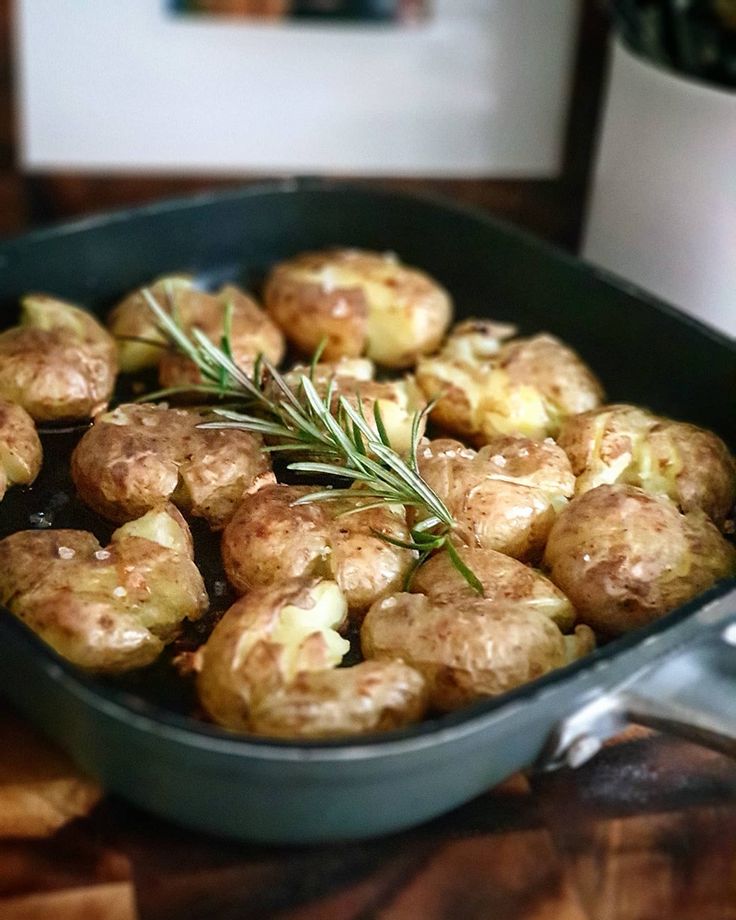 a pan filled with potatoes and topped with a rosemary sprig