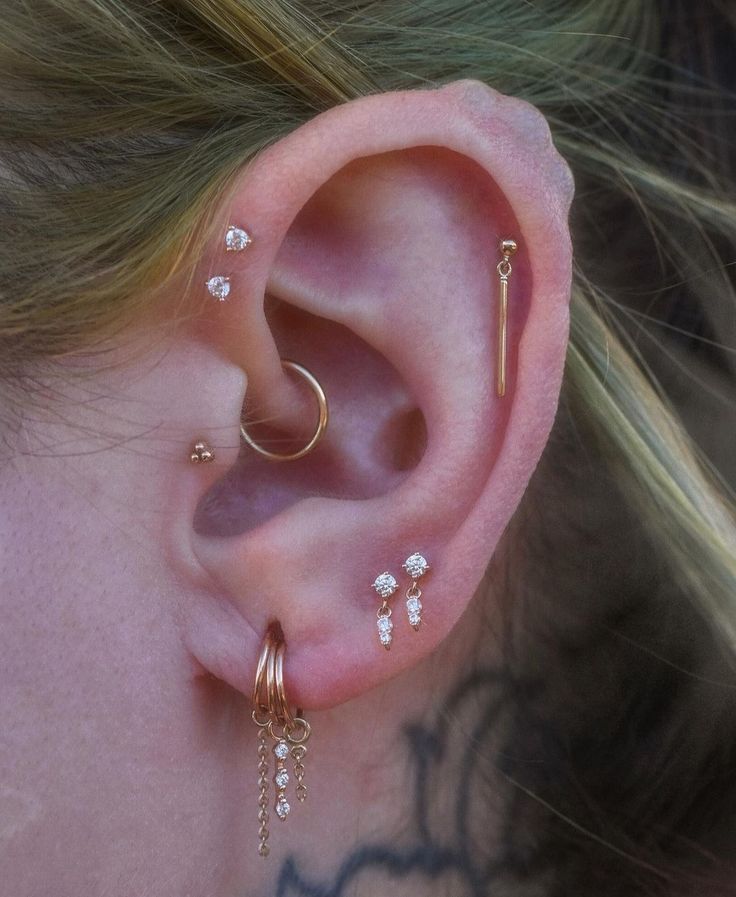 a woman wearing three different ear piercings on her left ear and the other one is in