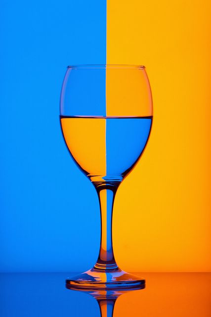 a wine glass sitting on top of a table next to a blue and yellow wall