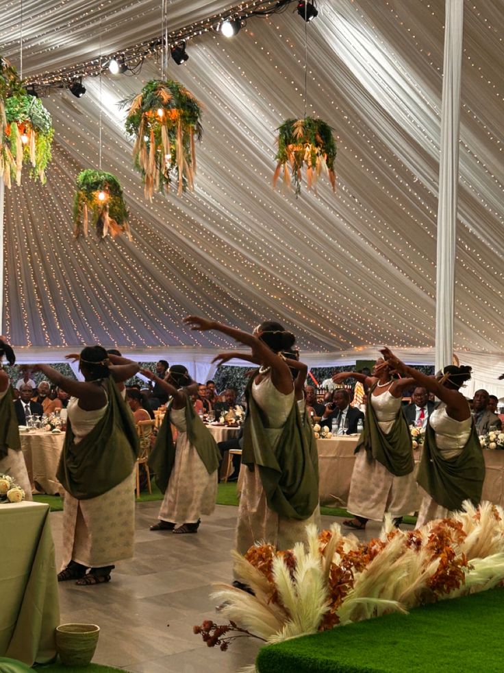 a group of people standing around each other in front of a white tent with lights