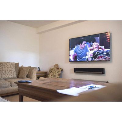 a flat screen tv mounted to the side of a wall next to a wooden table