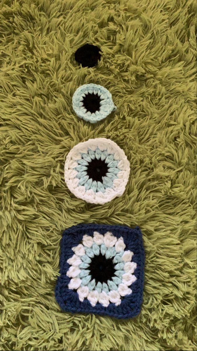 three crocheted eyeballs laying on top of a green carpet next to each other