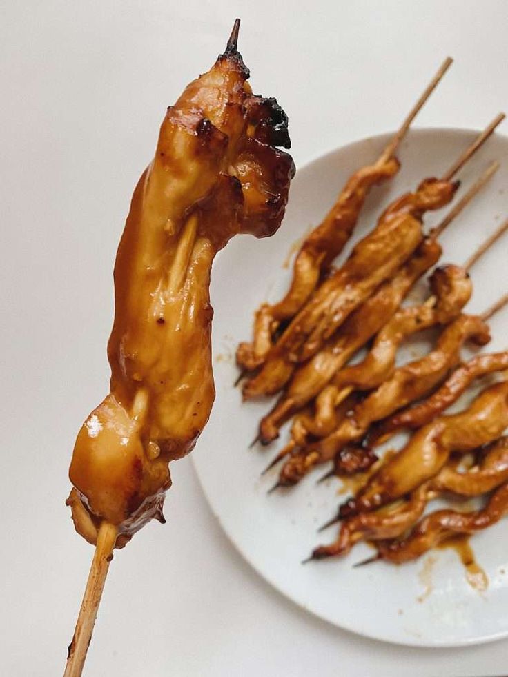 chicken skewers are being served on a white plate