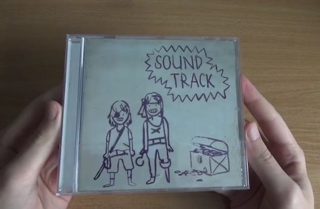 someone holding up a cd case with an image of two people on it and the words sound track written in black ink