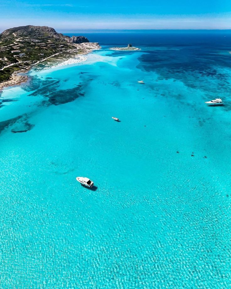 an aerial view of boats in the blue water