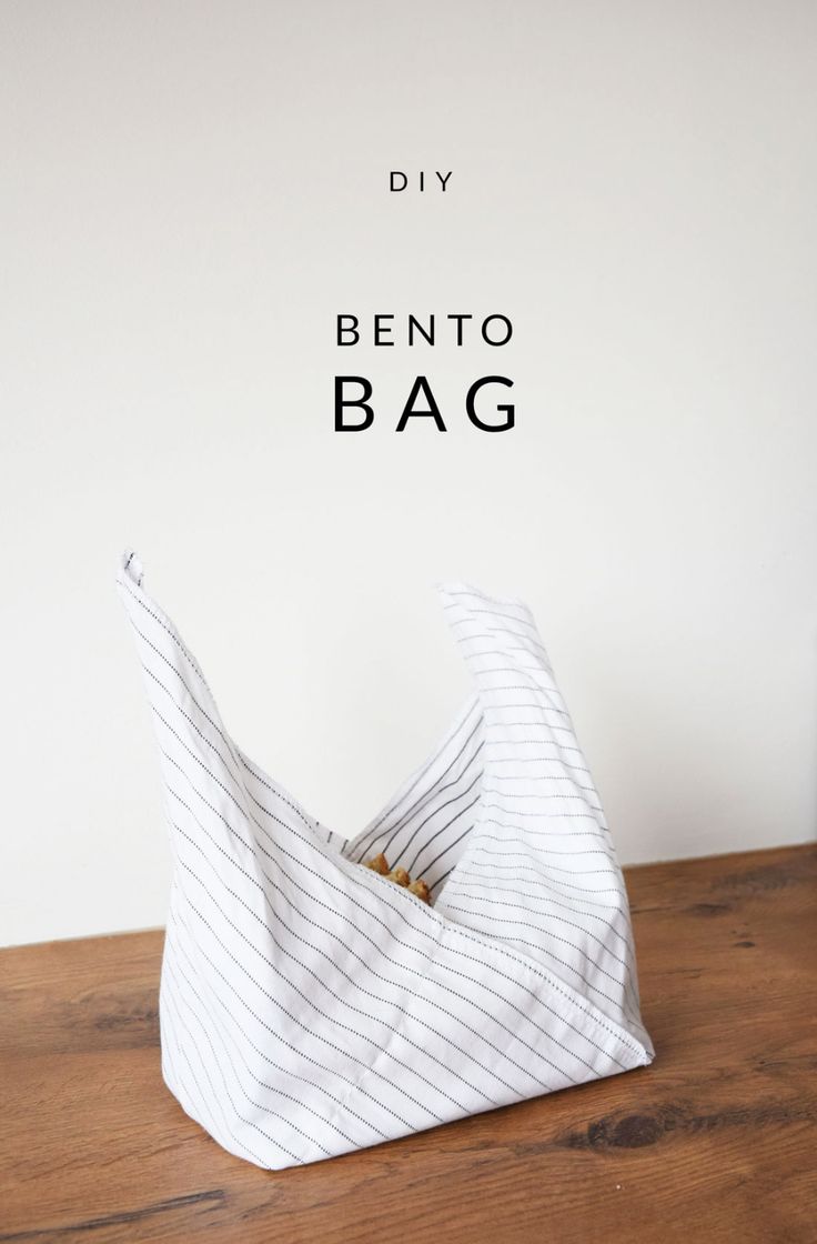 a white bag sitting on top of a wooden table next to a sign that says diy bento bag