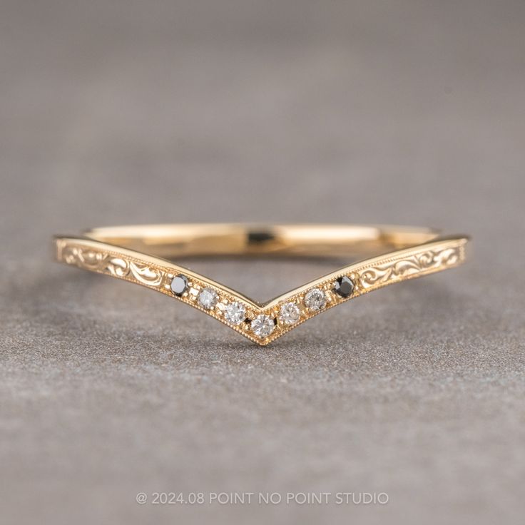 a gold wedding band with white diamonds on the side, sitting on a gray surface