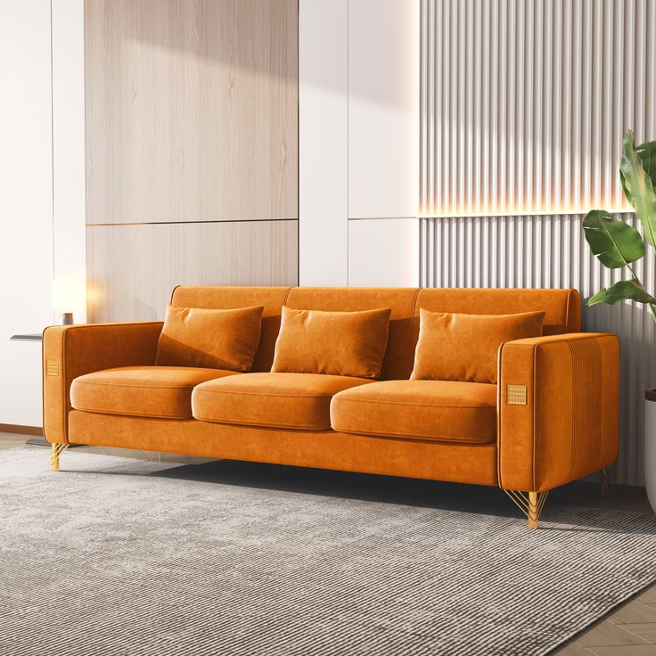 an orange couch sitting on top of a rug next to a potted plant