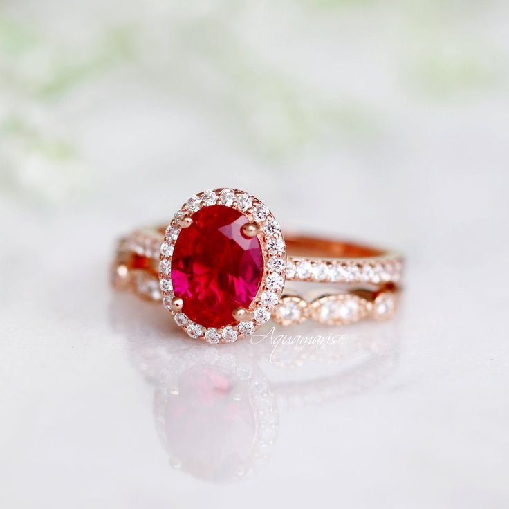 Beautiful Vintage Inspired Ruby Ring ►Base Metal: Sterling Silver (S925) ►Plating: 14K Rose Gold Vermeil ►Accented With Simulated Diamonds ►Can be paired with one or two half-eternity Milgrain bands of your choice Center Stone: Ruby Grade: AAA Stone Cut: Oval Gem size: 8.0 x 6.0 mm Carat Weight: 1.21 ct. Gemstone creation: 100% Genuine Lab-Grown Ruby Stone Origin: Russia ►Please be aware that plated jewelry can wear off over time, if this is a concern we would suggest going with the sterling sil Oval Ruby Ring For Wedding And Promise, Fine Ruby Jewelry For Wedding And Promise Occasions, 14k Rose Gold Gemstone Wedding Jewelry, Ruby Cluster Ring With Halo For Wedding, Fine Jewelry Ruby Ring With Halo Setting For Promise, Ruby Cluster Ring With Halo, Ruby Halo Cluster Ring For Wedding, Wedding Lab-created Ruby Ring With Prong Setting, Valentine's Day Wedding Ring With Accent Stones