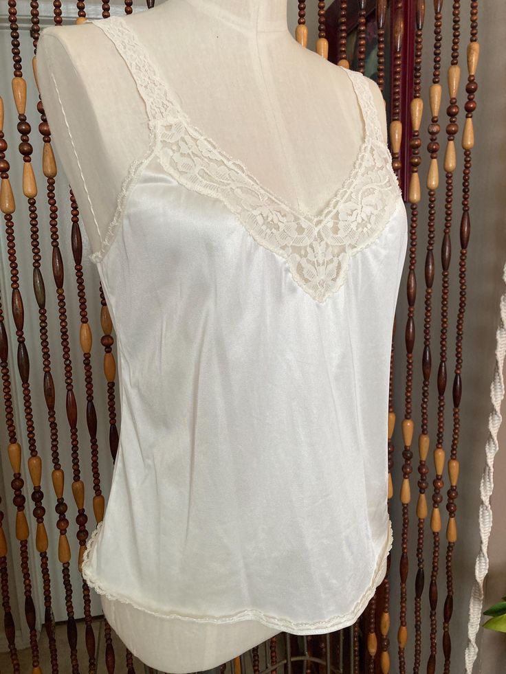 Sweet little cream colored camisole with stretchy lace straps. Brand is vanity fair, tag  says size 36/42, the dress form is an 8 and it is loose on it. Modern size large, or 10. it has some stretch. Lace V-neck Camisole, Cream Camisole With Built-in Bra And Spaghetti Straps, Summer Camisole With Lace Bodice, Summer Lace Bodice Camisole, Lace V-neck Camisole For Wedding Night, Feminine Fitted Lace Tank Top, Fitted Feminine Lace Tank Top, Lace Delicate Camisole, Feminine Summer Camisole With Lace Bodice